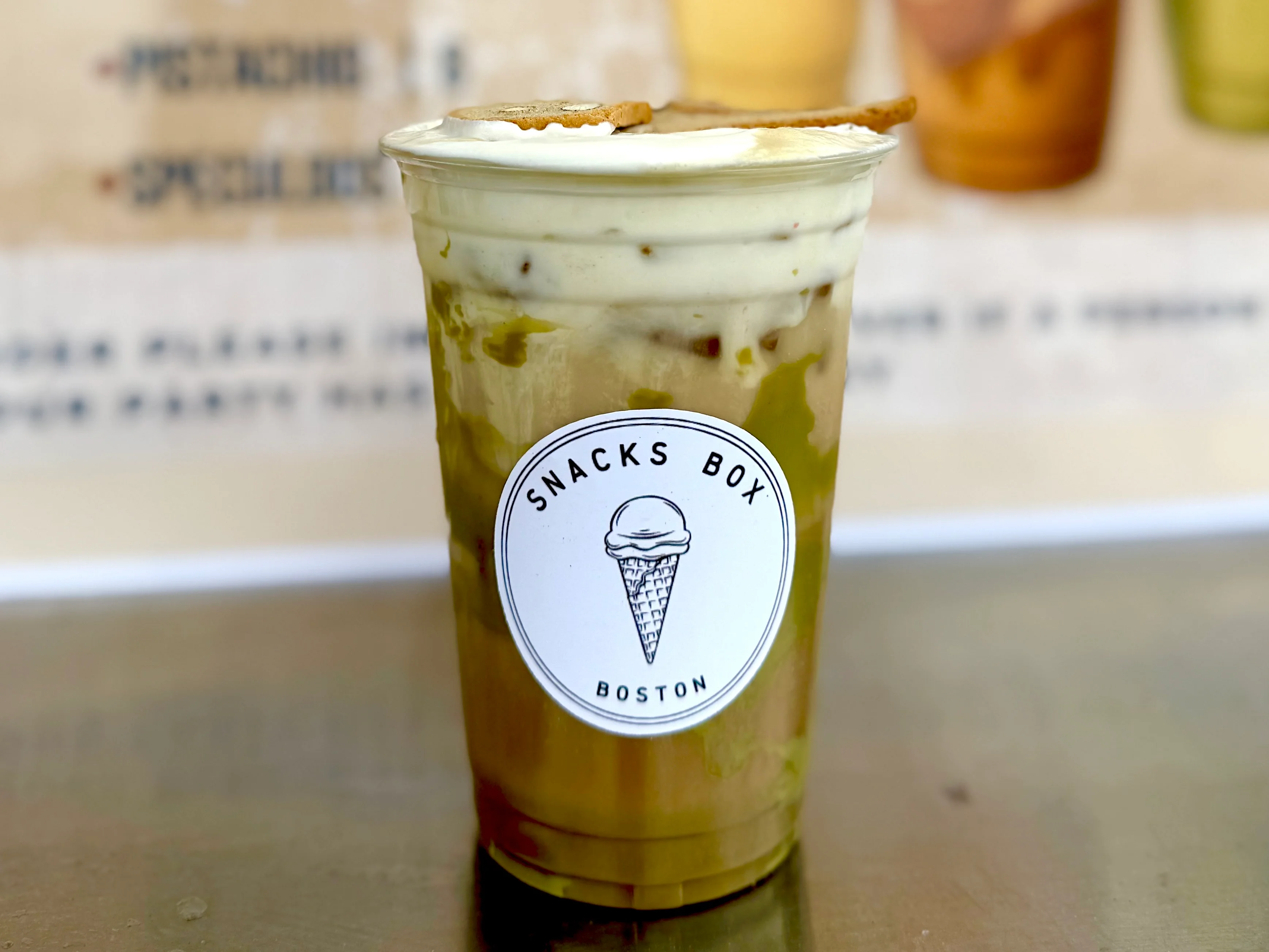 Iced latte in a SNACKSBOX Boston branded cup